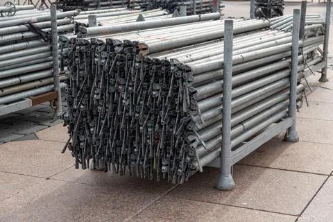 Large stack of metal scaffolding pipes and clamps on racks Stock Photos