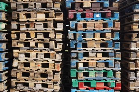 A large stack of multi-colored pallets next to the warehouse Stock Photos