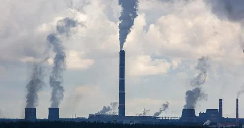 A large stack of smoke is coming out of a factory Stock Photos