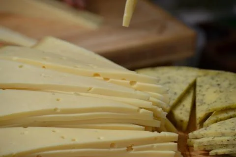 A large stack of thin, pale yellow cheese slices with small holes is shown in Stock Photos