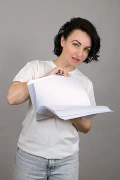 Large stack of white paper in teacher's hands, gray background close-up Stock Photos