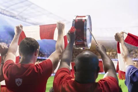 Large stadium crowd cheering players on football pitch during sunny day Stock Photos