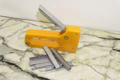 Large stapler and staples for construction work on white . Stock Photos