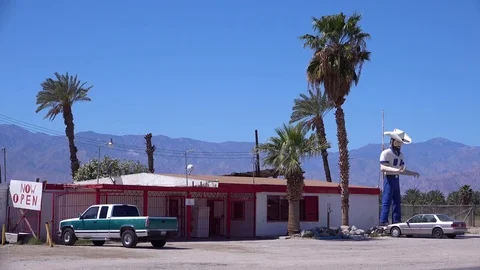 A large statue of a cowboy stands outside a desert bar or saloon. Stock Footage 79404018
