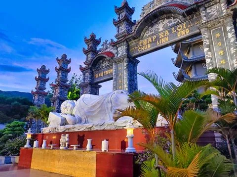 Large statue of a sleeping figure in a temple surrounded by greenery during.. Stock Photos