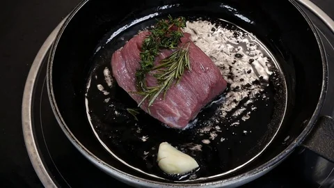 Large steak is fried in a frying pan in the kitchen of the restaurant in close Stock Footage 107184856