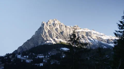Large steep snow-covered mountain surrounded by forest in the Alps, Switzerland Stock Footage 240139556