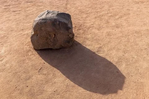 A large stone and its shadow on dry ground Stock Photos