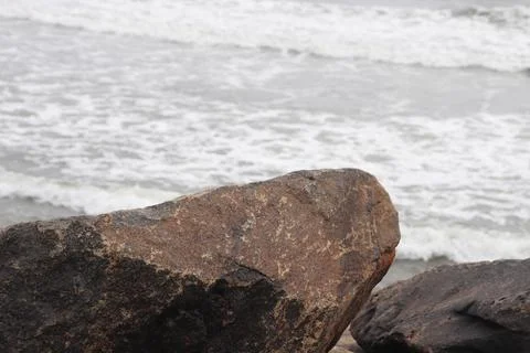 Large Stone on Beach with Sea Waves in Background Stock Photos