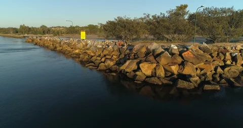 Large stone break wall at the mouth of a flowing river at low tide Stock Footage 110890347