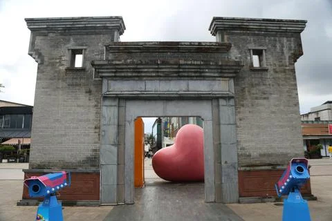 Large Stone Gateway Structure Framing Pink Heart Sculpture in Urban Public .. Stock Photos
