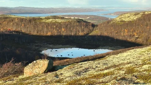 A large stone on a hillside and a lake in the autumn tundra. Video stock 76102385