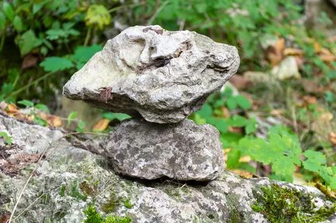 A large stone lying on a small stone in a park Stock Photos