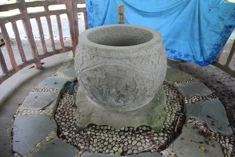 A large stone pot is placed on the ground, surrounded by small stones with .. Foto stock
