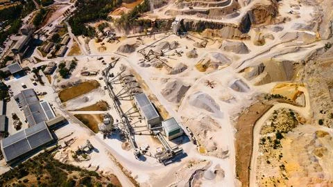 Large stone quarry shows mining activity from above in sunny weather. Worke.. Stock Photos