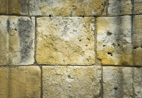 Large stone wall of an old building, with a lot of texture and warm tones. Stock Photos