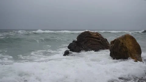 Large stones on the seashore, against which waves break during a storm. Stock Footage 324583734