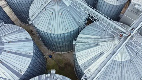 Large storage silos are arranged in a pattern at a farming facility during Stock Footage 341384764