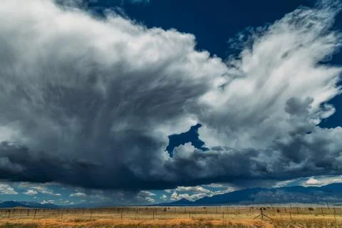 Large Storm cloud building over mountain range with rain falling Fotos de archivo