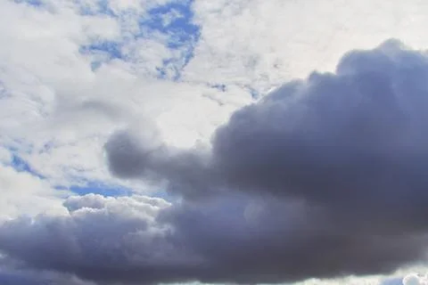Large storm clouds in the blue sky, lights on the clouds in the sky. Stock Photos
