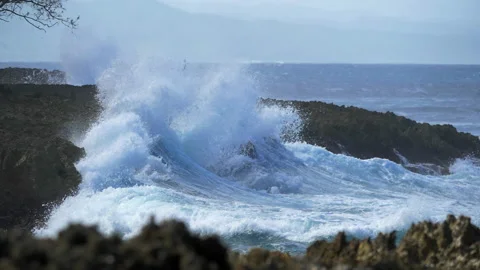 A large storm wave rolls onto a steep rocky shore in slow motion. A powerful sea Stock Footage 222579174