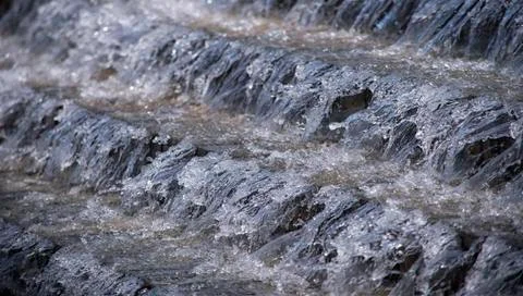 A large stream of water flows down the steps of the cascade. 스톡 사진