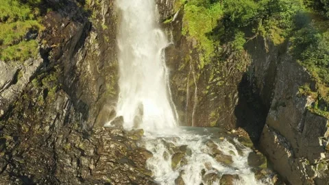 Large streams of waterfall among the branches of trees fall down in close-up. Stockbeeldmateriaal 269299016