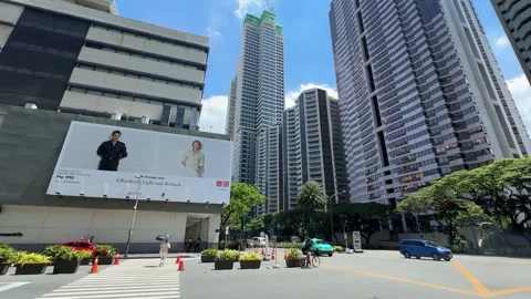 Large street billboard by city intersection with Makati skyscrapers skyline 4k Stock Footage 337443504