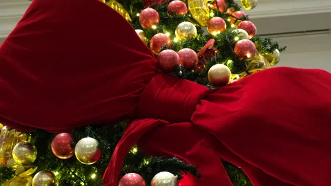 A large, striking red bow elegantly wrapped around a festive Christmas tree Stock Footage 326965663