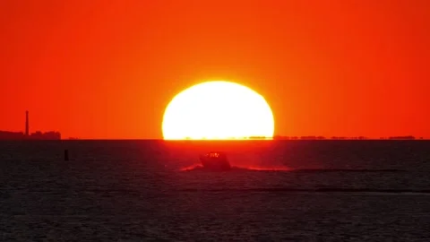 Large sun disk seen at horizon, motorboat race and stop, high contrast shot Stock Footage 161793926