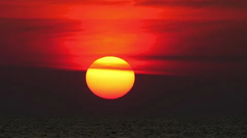 Large sun setting over ocean horizon with dramatic red sky 库存影片 335879164