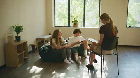 A large sunlit room hosts a therapy session, where a woman talks to the Stock Footage 345009750