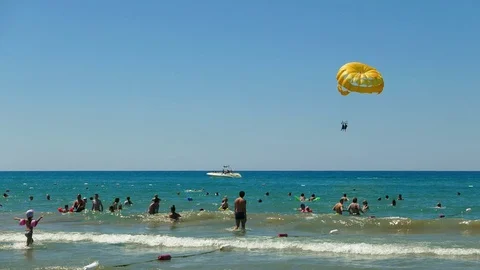 Large sunny sandy ocean beach. Parasailing. Holidaymakers, tourists in the sea  Stock Footage 77917268