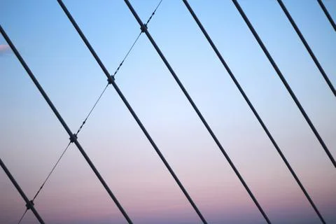 Large support wires of a bridge during sunset forming a pattern 스톡 사진
