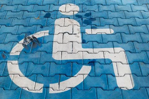A large symbol for accessibility is seen on a blue surface in an outdoor ar.. Фото