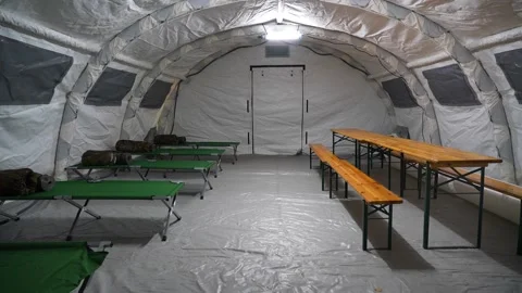 A large tent with folding beds on which sleeping bags lie Stock Footage 320818592