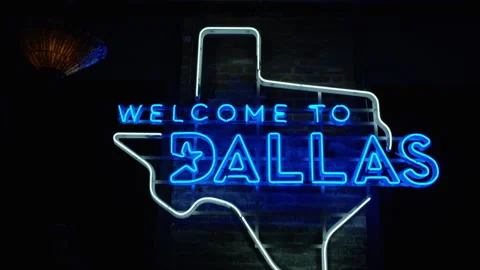 A large Texas shaped neon light glows blue and reads: Welcome to Dallas Stock Footage 280143693