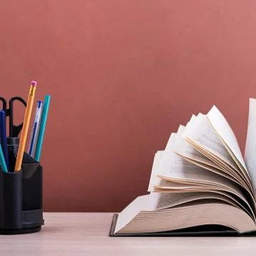 A large thick book with the pages spread out like a fan and a stand with pens Stock Photos