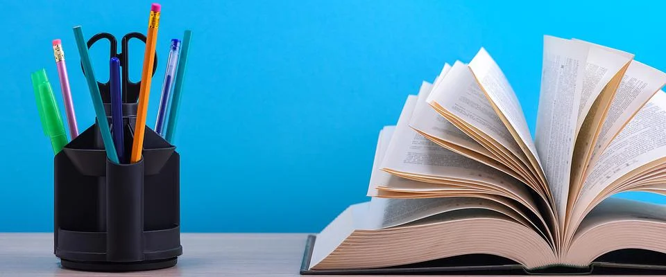 A large thick book with the pages spread out like a fan and a stand with pens Stock Photos