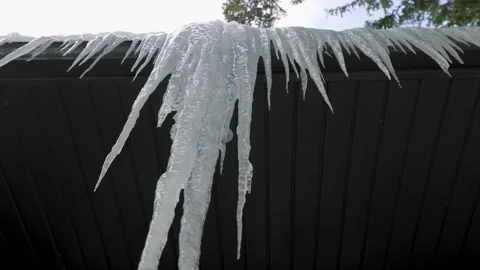 Large Thick Icicles Overhang Edge of Roof with Cloudy Sky in Background Vídeo Stock 172479837