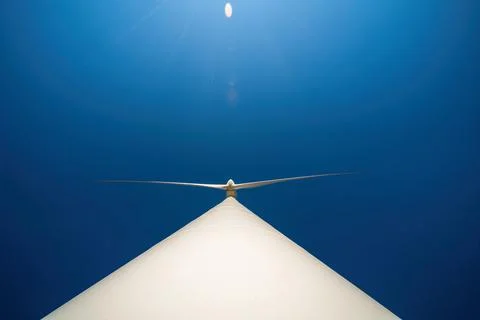 Large three-bladed horizontal-axis wind turbine against clear blue sky. Drama Foto stock