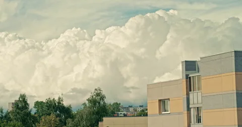 Large towering cumulus clouds above modern residential buildings and trees Stock Footage 340997557