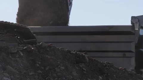 Large track hoe drops dirt into the dump truck.  Stock Footage 253281254