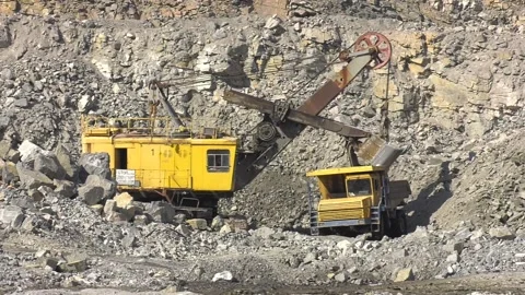 A large tracked excavator in a quarry open pit mining of granite stone Video stock 102673254