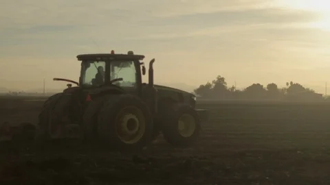 Large Tractor with Driver at sunset Plowing Land Stock Footage 94642827