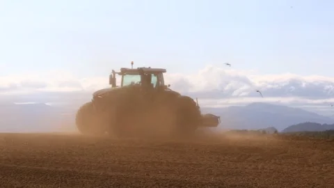 Large tractor plowing dry field in strong wind generating dense dust Stock Footage 341977451