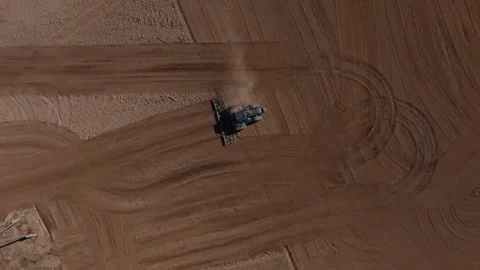 Large tractor pulls cultivator across field, dust and patterns Video stock 337583497