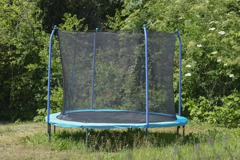 Large trampoline with a safety net in the backyard garden Stock Photos