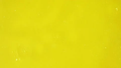 Large transparent bubbles slide along smaller ones, moving them on a yellow Stock Footage 219965081