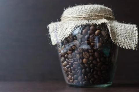 Large transparent jar with coffee beans closeup Stock Photos